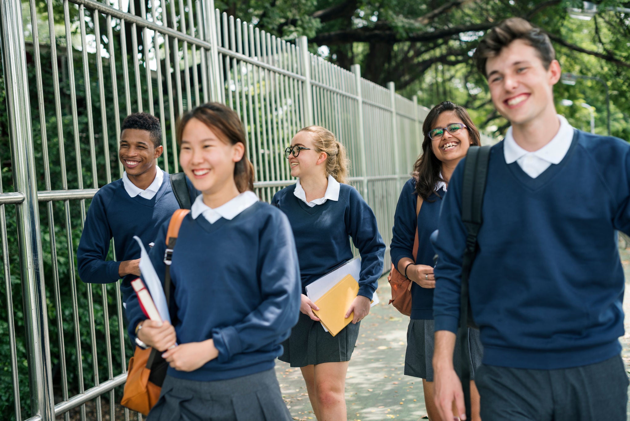 Group of five students walking to school smiling