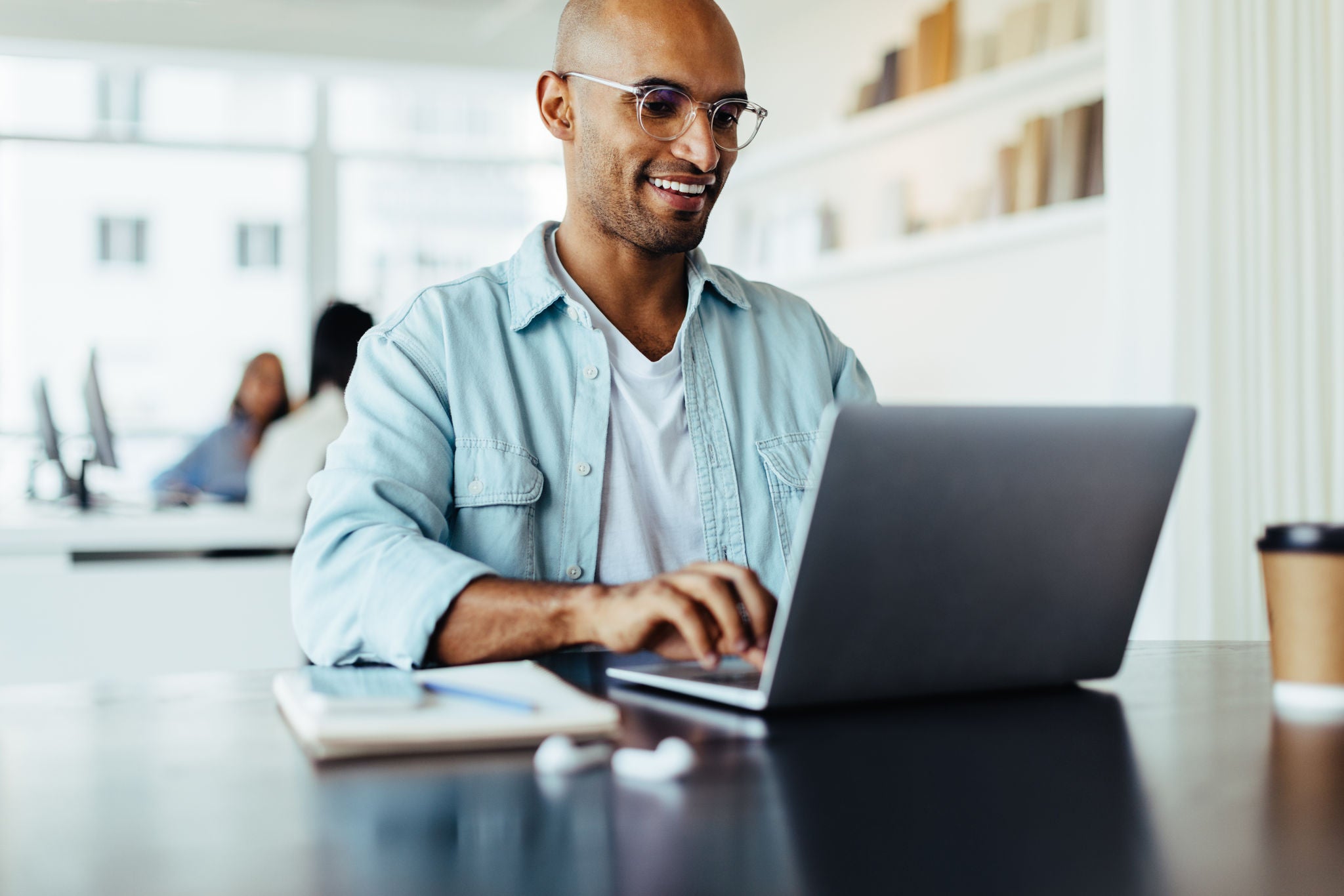 Creative male designer working on his laptop while sitting in an office. Young business man working on a new web design.