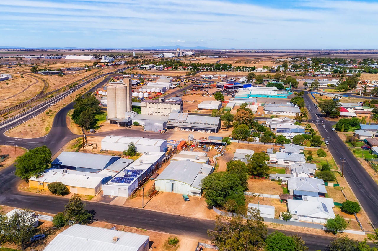 An aerial photo of Moree shows blue sky set against a dry landscape with many buildings in the foreground, including a tall silo.